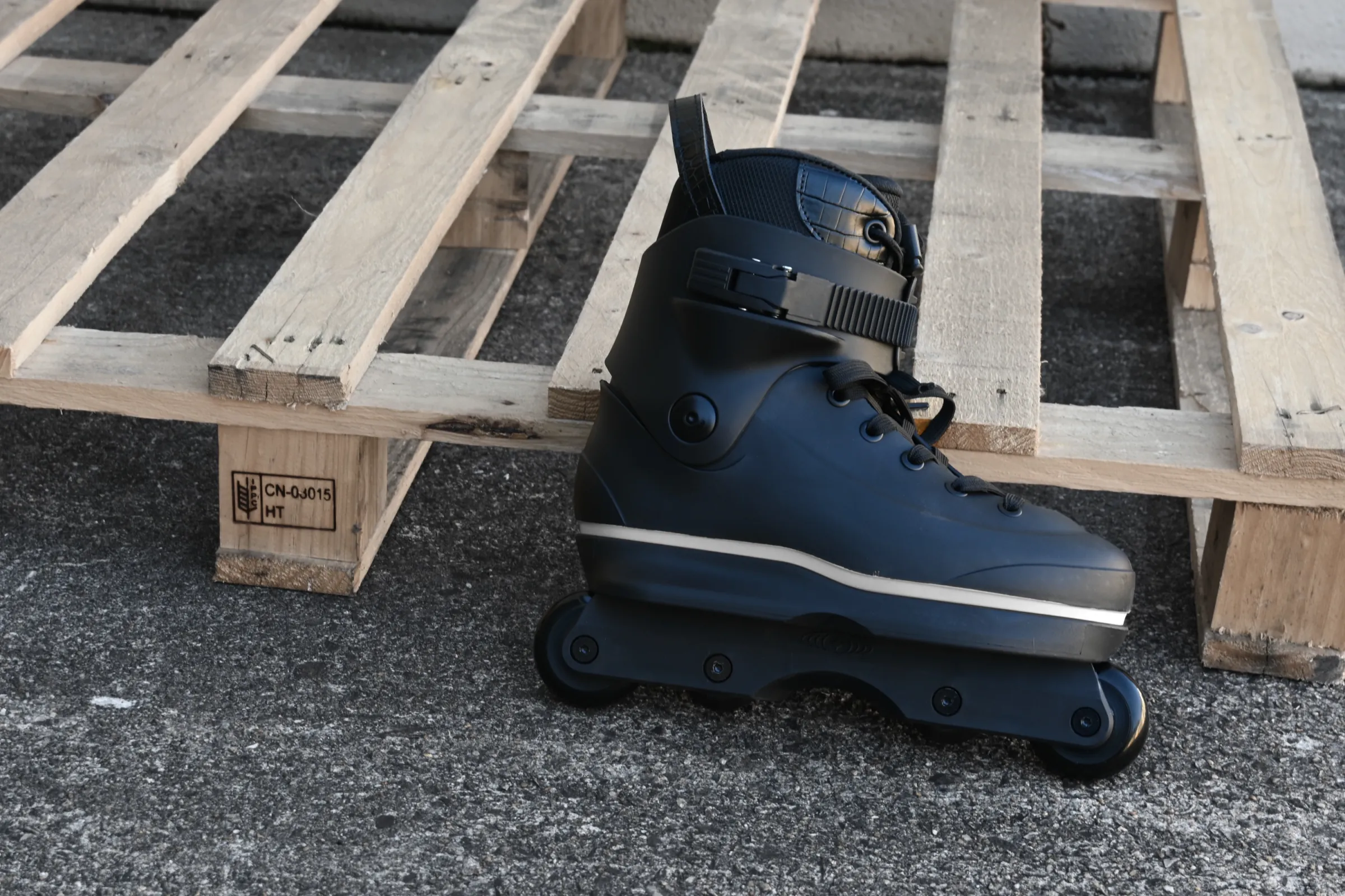 Black Omni V3 skate in front of wooden pallets